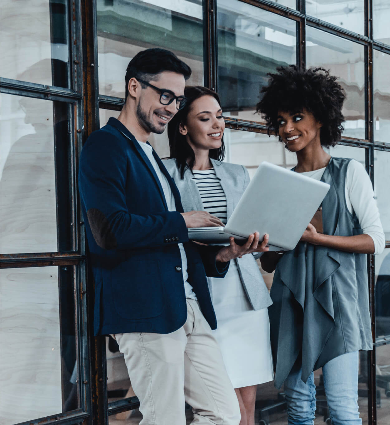 Man and two woman having a discussion over a laptop.